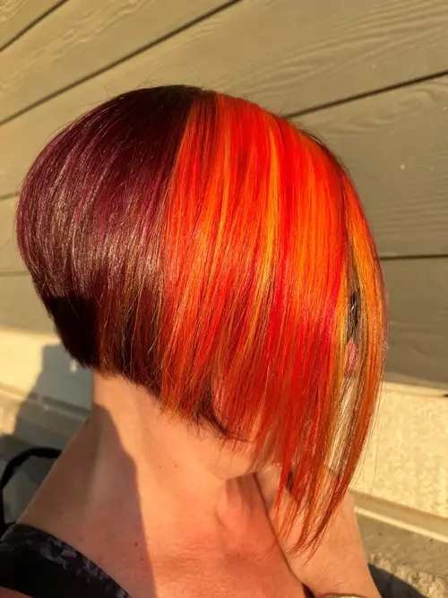 Phoenix hair color brings this short asymmetrical bob to life with deep dark red, fiery orange, and (..)